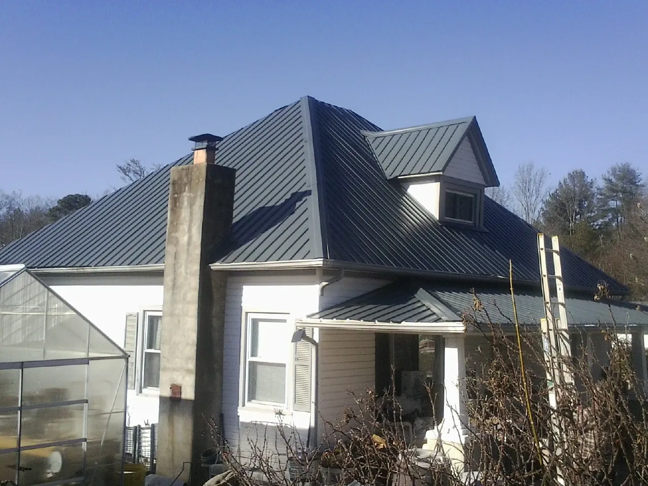 Dark blue standing seam metal roof on a white farmhouse with dormer — Slate & Tile Roof Repair by Roofing Brothers in Valley City