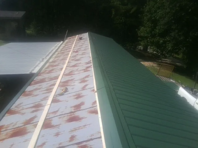 Old rusted panels beside newly installed green metal roofing — Wind Damage Roof Repair by Roofing Brothers in Valley City
