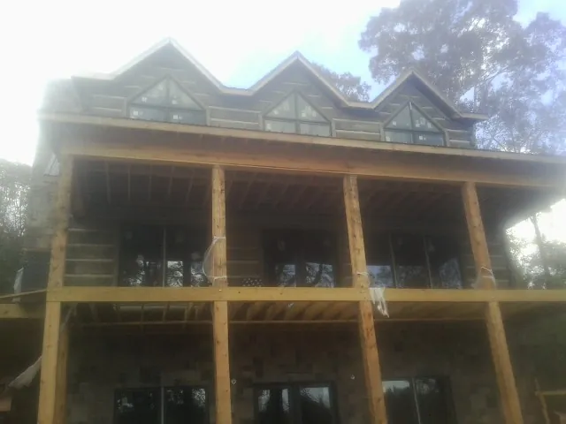 Dormers and porch framing on a large log home under construction — Roof Coating work by our crew in Valley City