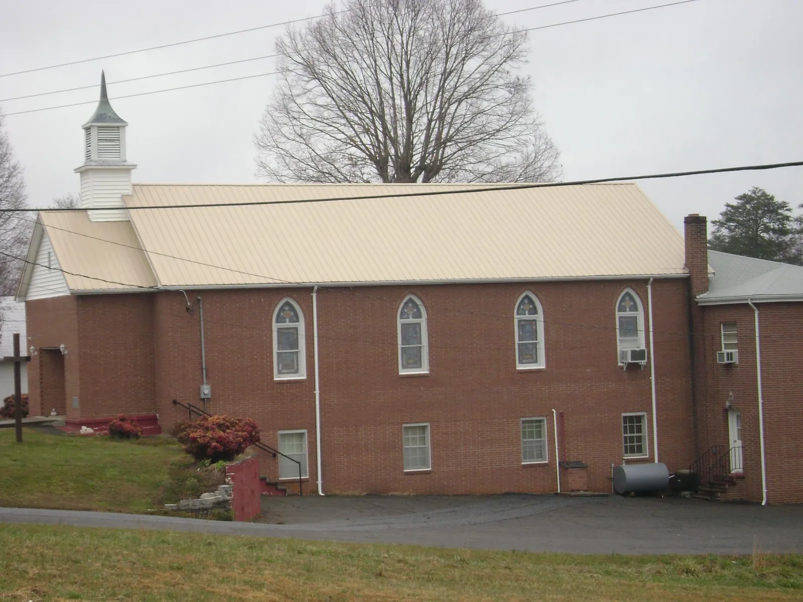 New tan metal roof on a brick church with a white steeple in Valley City
