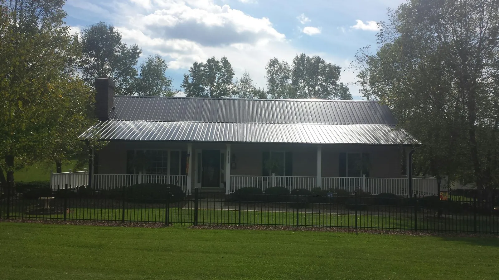 Gray metal roof on a brick ranch with a full width front porch — Gutter Guard Installation work by our crew in Valley City